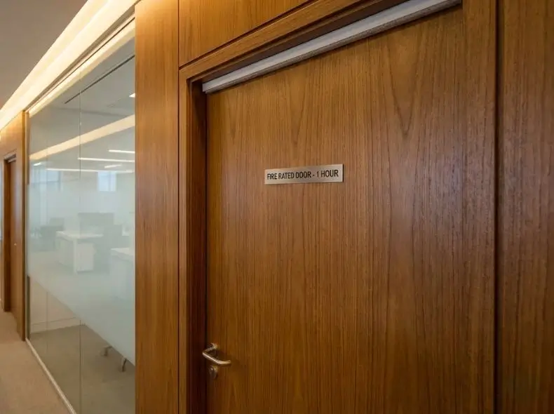 Elegant wooden fire-rated door with veneer finish installed in a modern office corridor for fire safety and aesthetics.