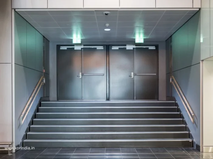 Professional installation of commercial fire doors in office building corridor showing proper NBC compliance